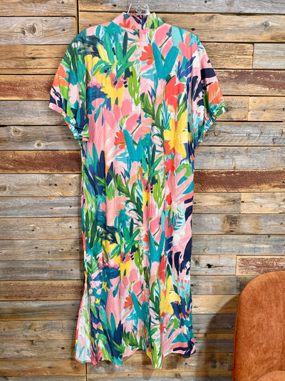 Colorful floral dress hanging against a wooden wall.