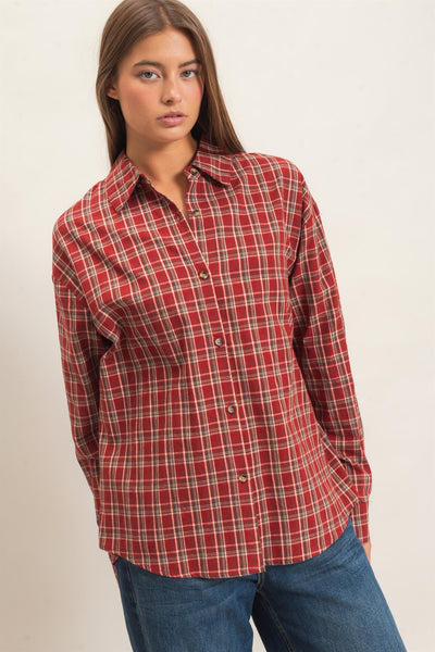 woman wearing a plaid shirt and jeans in front of a light background