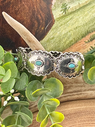 fashion concho stretch bracelet with turquoise accents on a wooden background with greenery