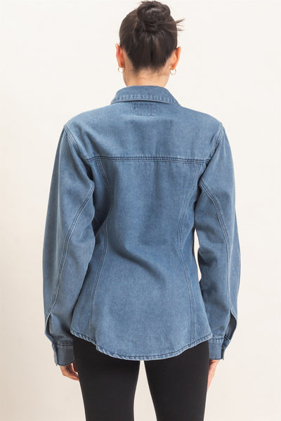 back of model wearing button down denim jacket and black pants with a light background