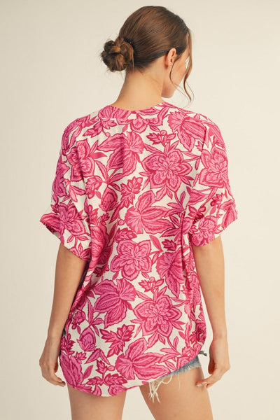 back of model wearing a pink & white floral top with cutoff denim shorts