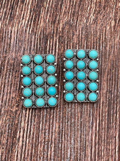 Pair of turquoise stone earrings on a wooden surface
