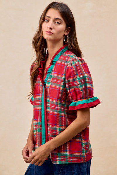Woman wearing a red plaid shirt with green accents on a beige background