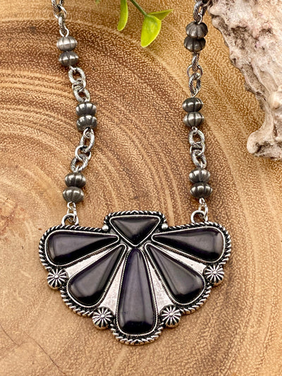 Necklace with black and silver pendant on a wooden surface
