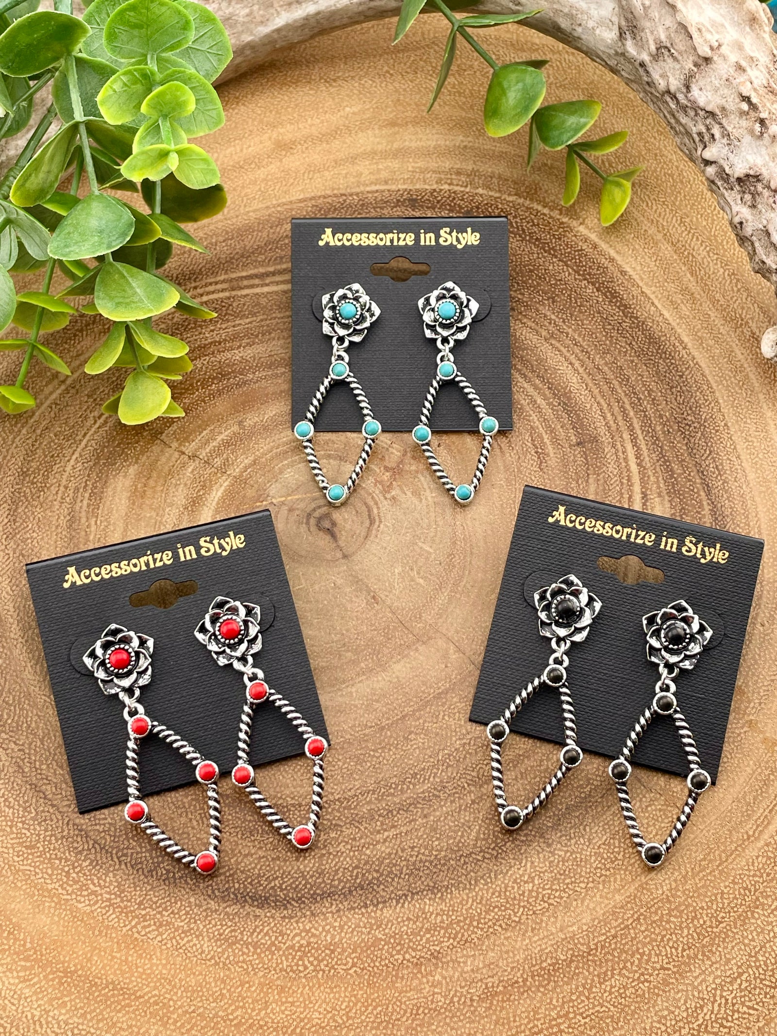 Three pairs of earrings on 'Accessorize in Style' cards with a wooden background.