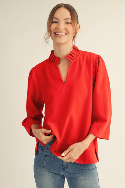 model wearing a red blouse & jeans with tan background