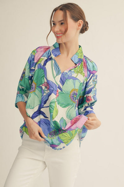 model wearing a blue floral top & white pants