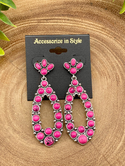 Pink earrings on a 'Accessorize in Style' card against a brown background