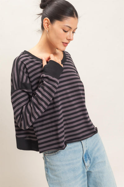 model wearing a black striped sweater and jeans with a light background