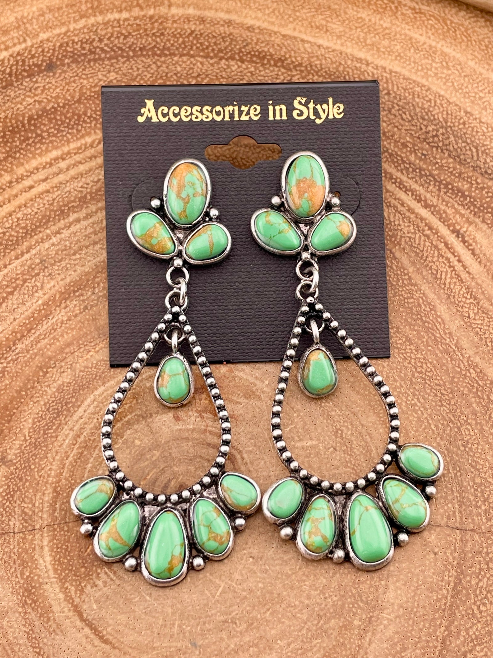 teardrop earrings with green stones on a wooden background