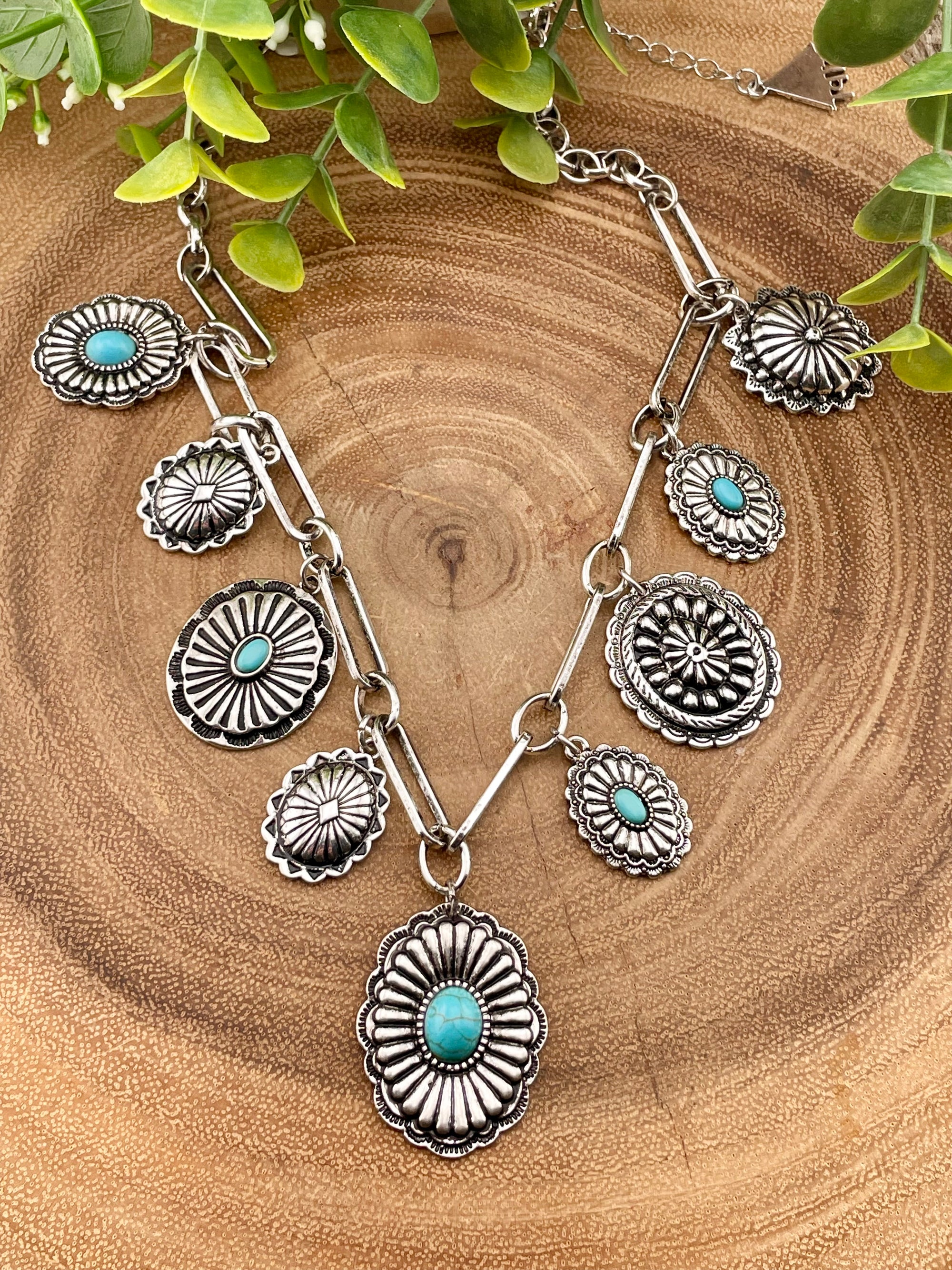 silver and turquoise charm necklace on a wooden surface