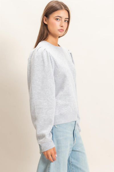 model wearing heather gray top and jeans in front of a light background