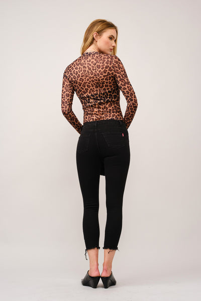 Woman wearing a leopard print top and black pants on a white background