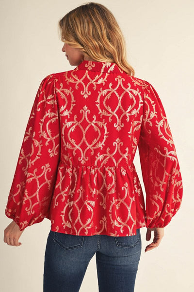 back of model wearing red and gold puff sleeve blouse with jeans in front of a beige background