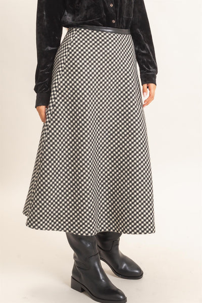 model wearing a black top and black checkered skirt with black boots