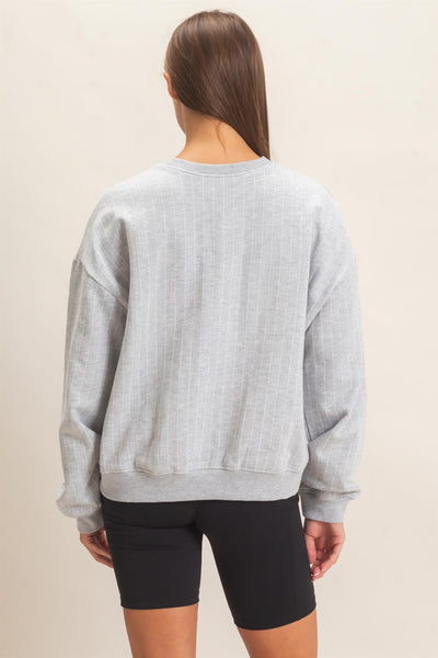 back of model wearing gray striped sweatshirt and black shorts with a light background