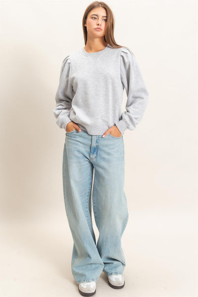 model wearing heather gray top and jeans in front of a light background