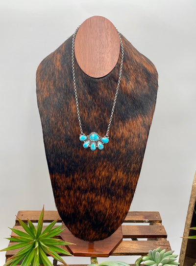 Necklace with turquoise stones on a wooden mannequin bust against a white background