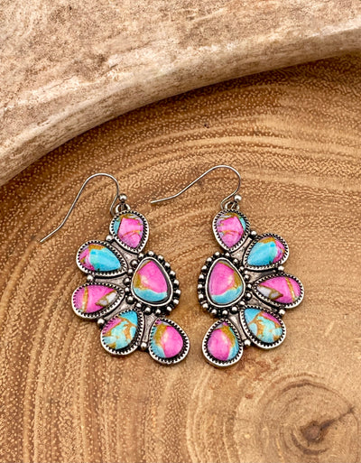 Multicolored teardrop earrings on a wooden surface