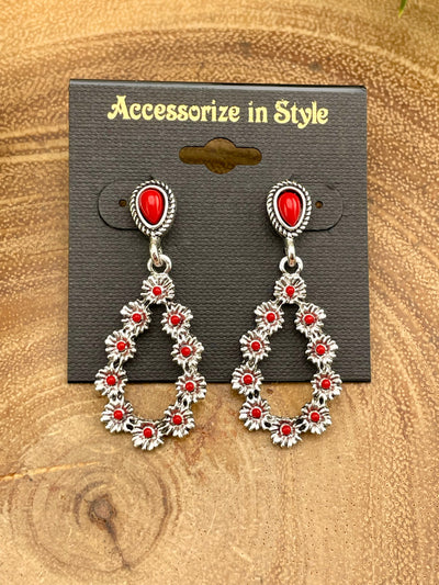 Pair of silver earrings with red stones on a 'Accessorize in Style' card, placed on a wooden surface.