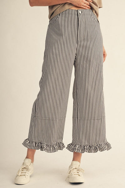 Striped pants with ruffled hem worn by a person on a beige background