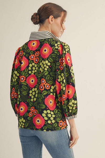 model wearing black stripe & dark floral blouse with denim pants on a light background