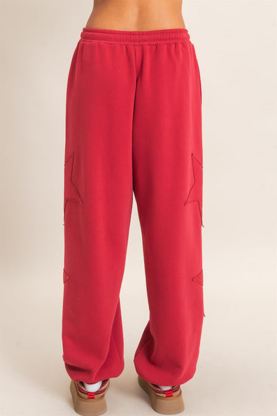 back view of model wearing red start patch joggers with a light background