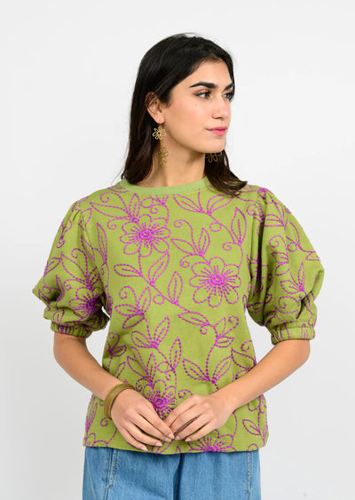 Woman wearing a green floral blouse with purple flowers on a white background