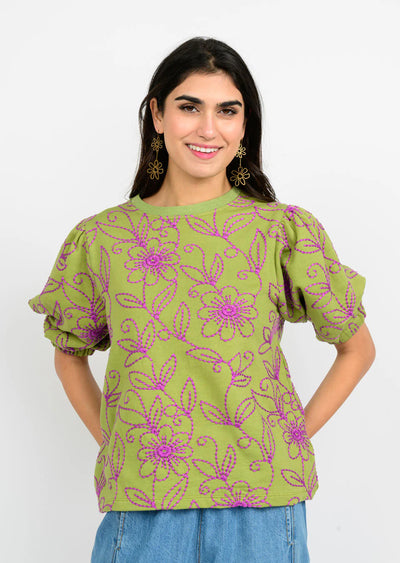 Woman wearing a green floral blouse with purple details on a white background