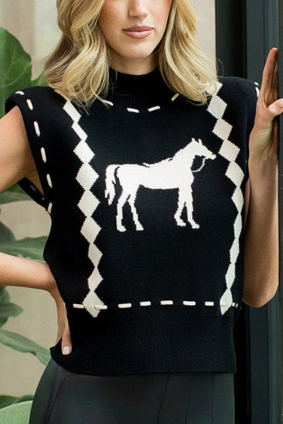 Woman wearing a black sleeveless sweater with a horse design, standing indoors.