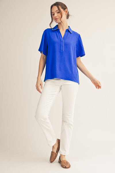 model wearing a royal blue v neck blouse with white pants