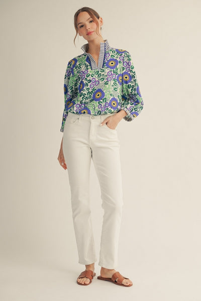 model wearing blue stripe & floral blouse with white pants on a light background