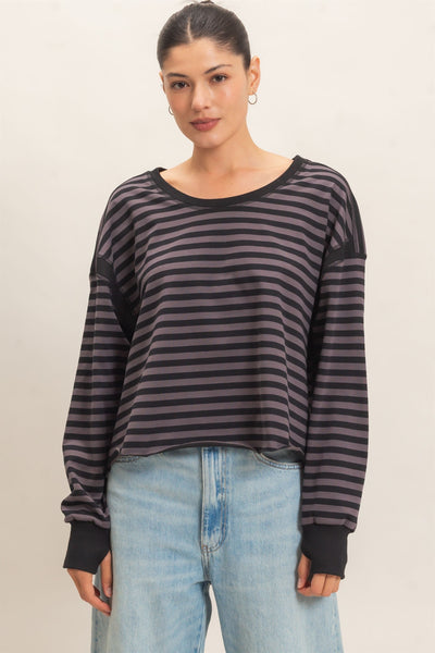 model wearing a black striped sweater and jeans with a light background