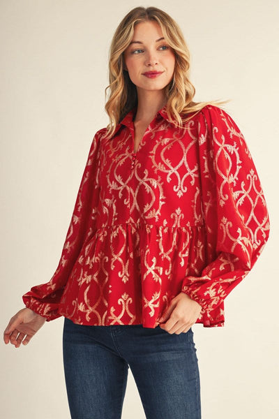 model wearing red and gold puff sleeve blouse with jeans in front of a beige background