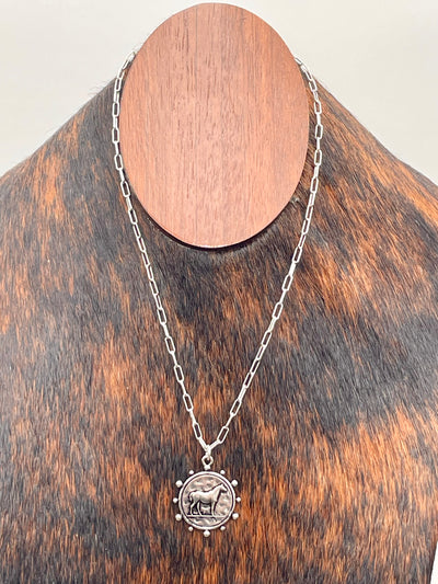 Silver necklace with a horse coin pendant on a cowhide bust