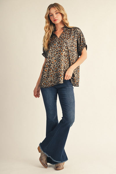 Woman wearing a leopard print top and blue jeans on a beige background