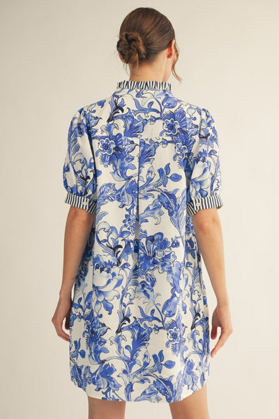 model wearing a blue & white floral dress with stripe accents on a light background