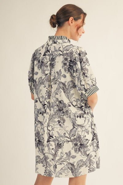 model wearing a black & white floral dress with stripe accents on a light background