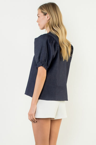 Woman wearing a navy blue top and white shorts on a light gray background