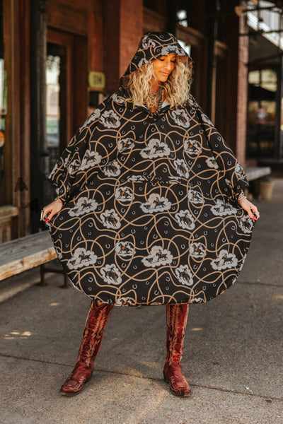 Woman wearing a black patterned coat and red boots on a street.