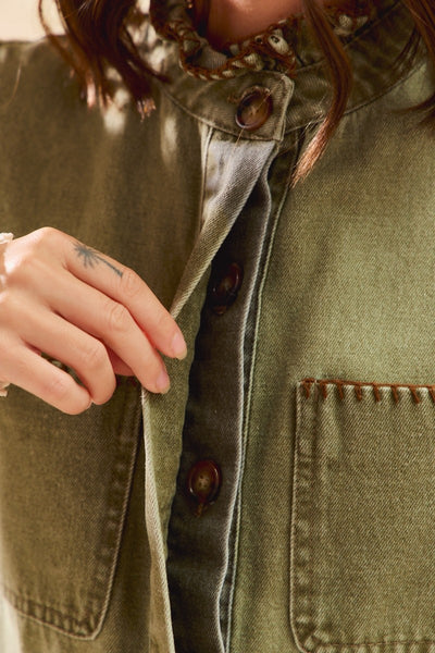 Close-up of a person wearing a green jacket with buttons and a pocket.