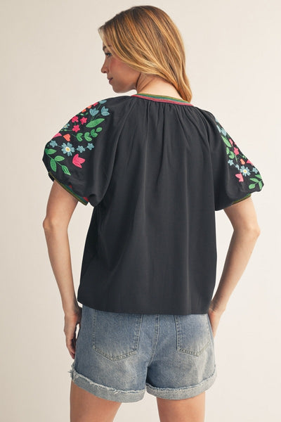 model wearing black top with embroidery & cuffed denim shorts