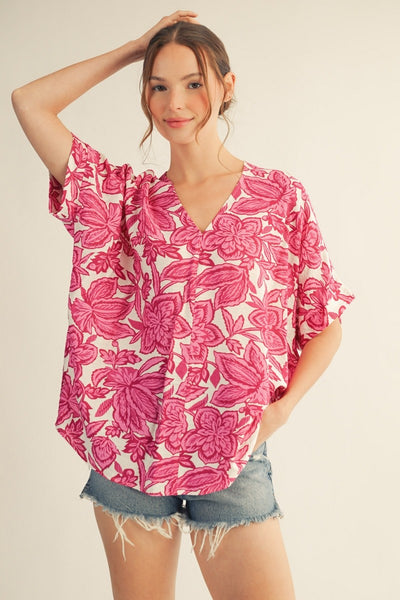 model wearing a pink & white floral top with cutoff denim shorts