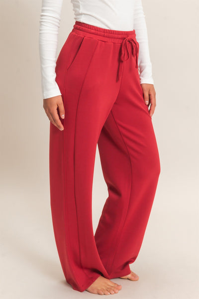 model wearing a white shirt & red pants with a light background