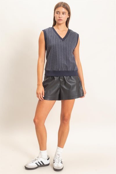 model wearing a striped v neck sleeveless top with black shorts & tennis shoes on a light background