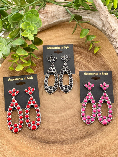Three pairs of earrings on cards with 'Accessories in Style' branding, displayed on a wooden surface with greenery.