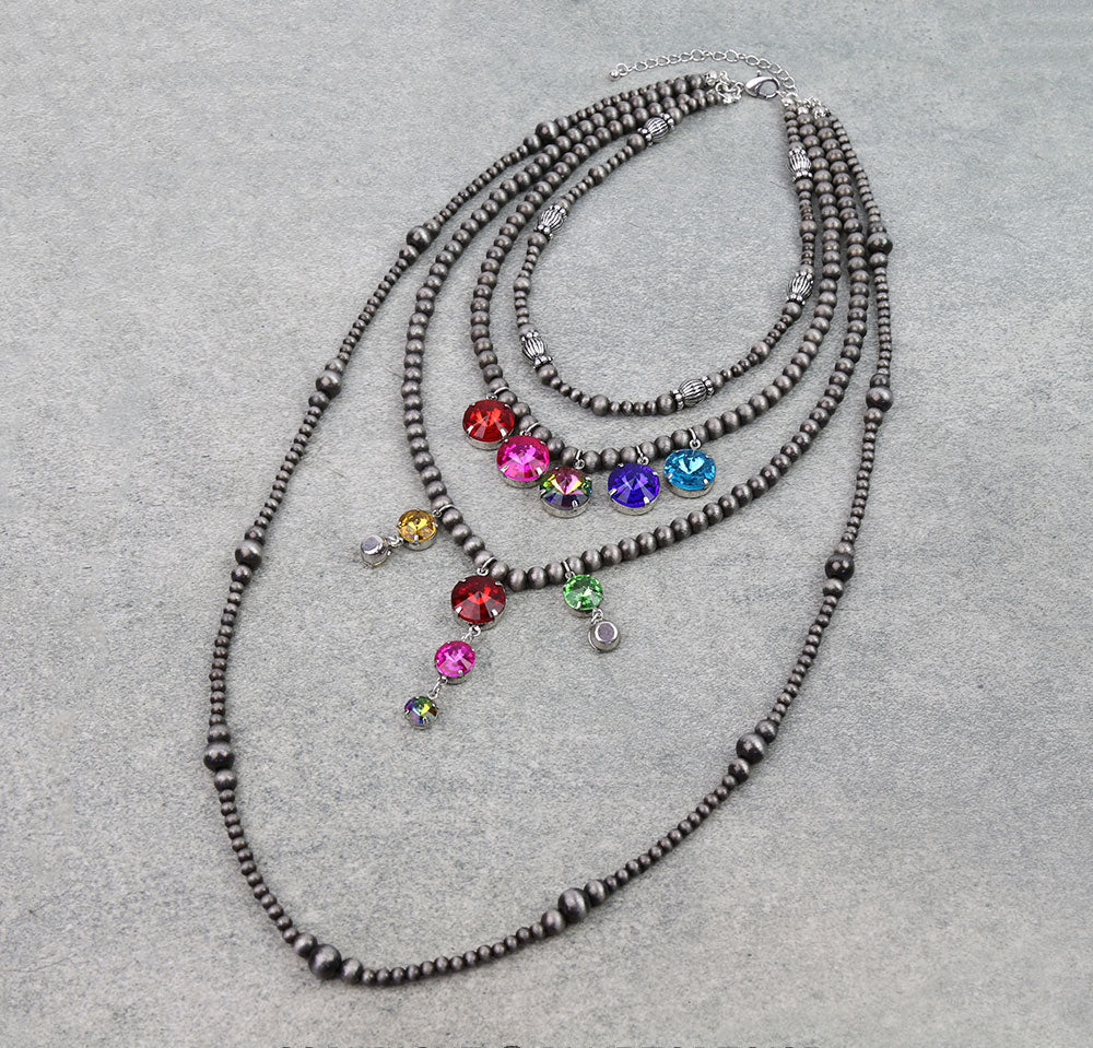 Four strand multi color rhinestone necklace on a gray background.