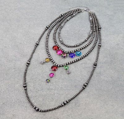 Four strand multi color rhinestone necklace on a gray background.