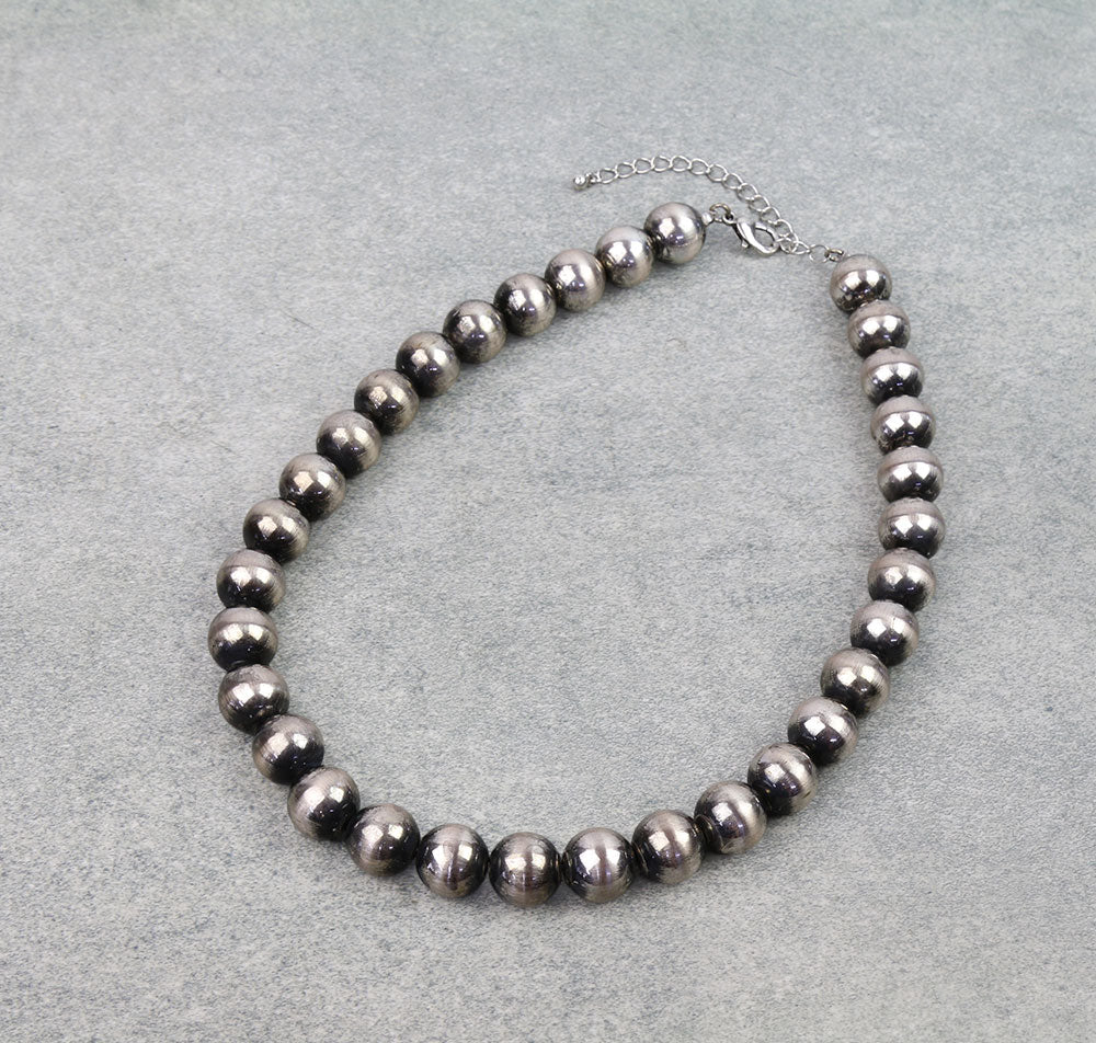 Necklace with dark beads on a gray background