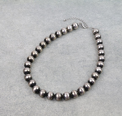 Necklace with dark beads on a gray background
